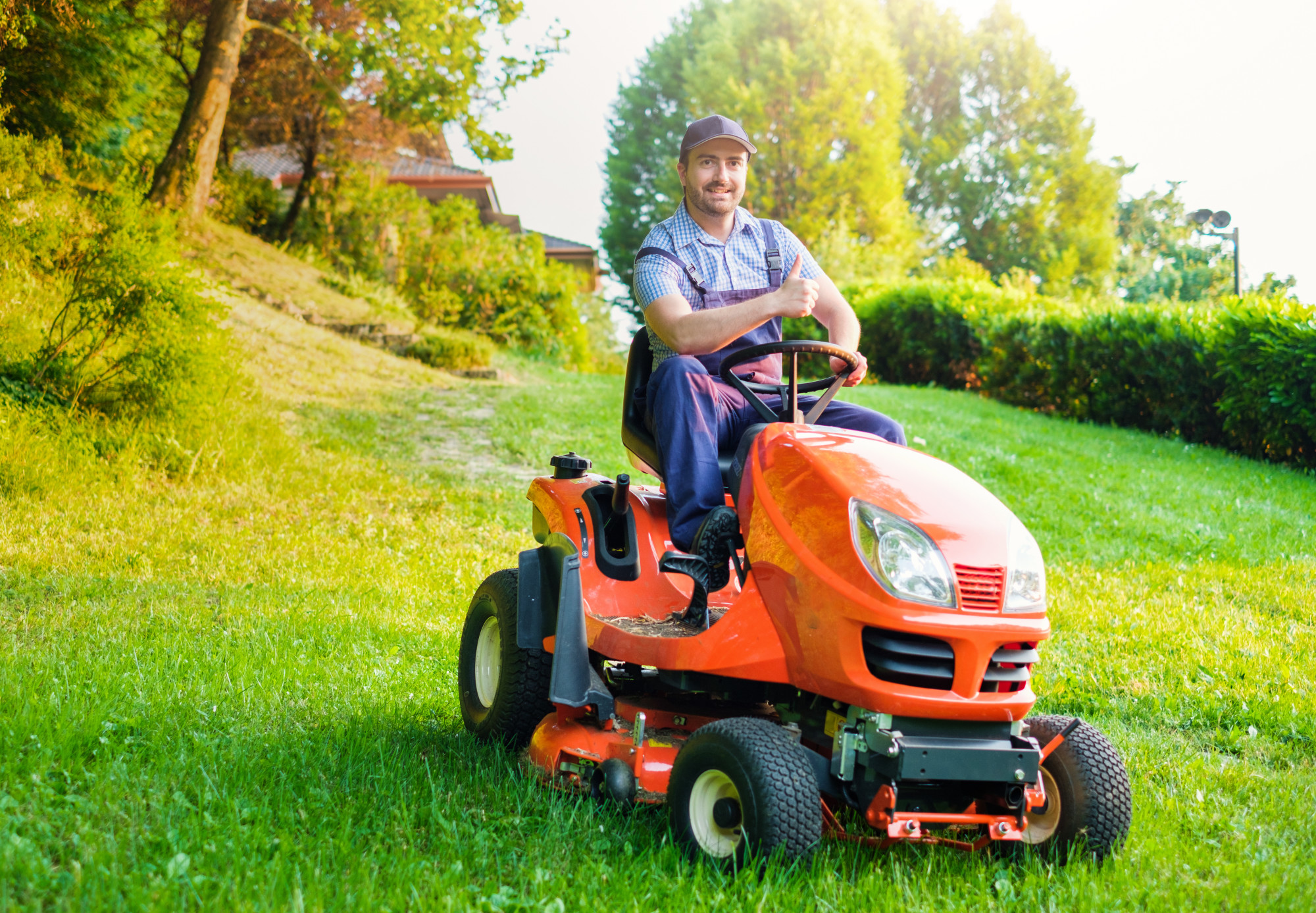 Gardener driving a riding lawn mower in a garden